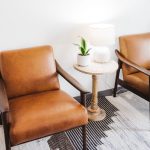 Vertical shot of brown chairs with white lamp and a house plant in a table
